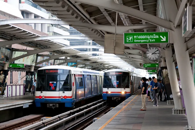 A BTS Skytrain arriving at an elevated Bangkok platform